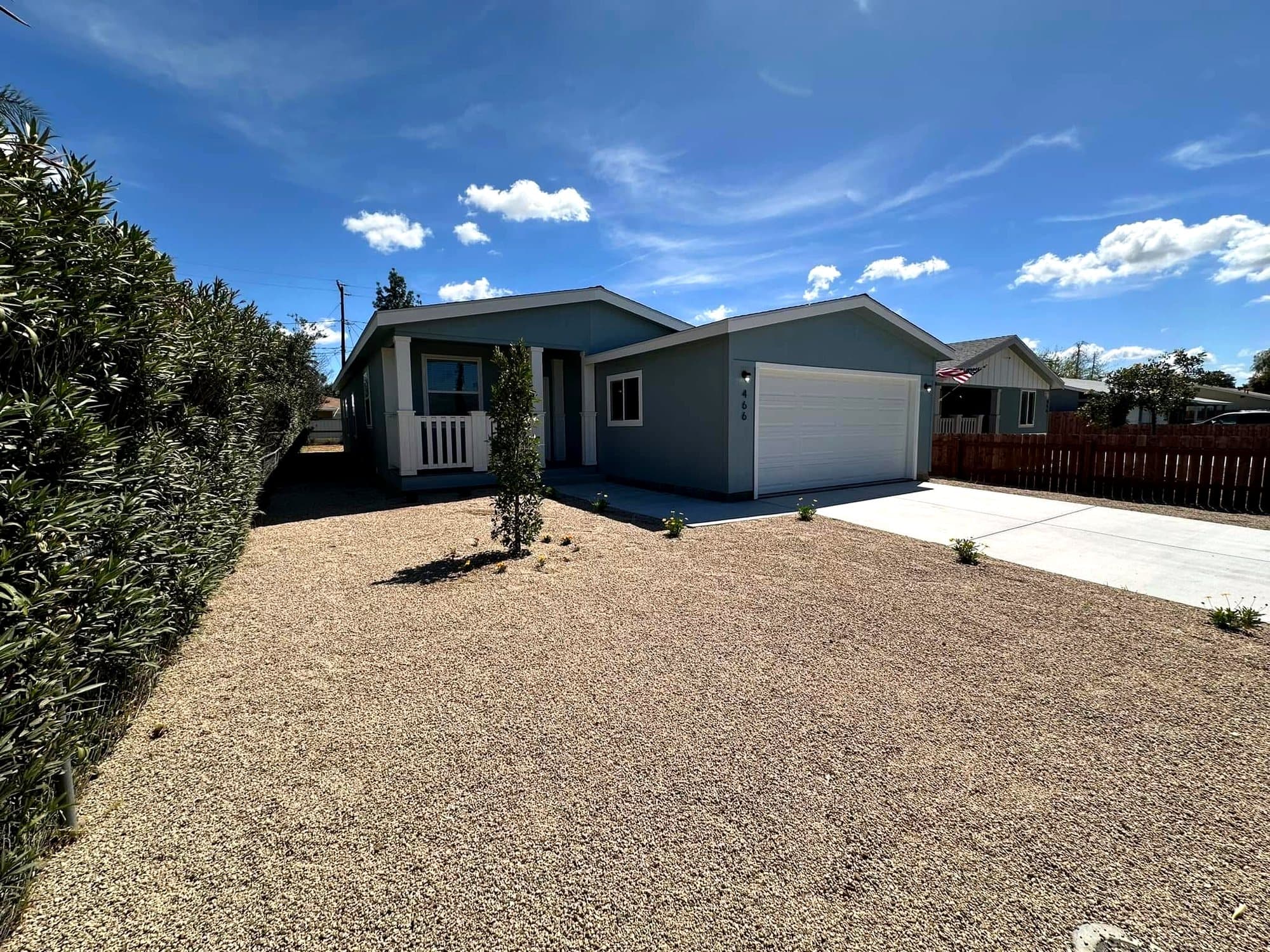 Blue-gray manufactured home with a white garage door and small porch
