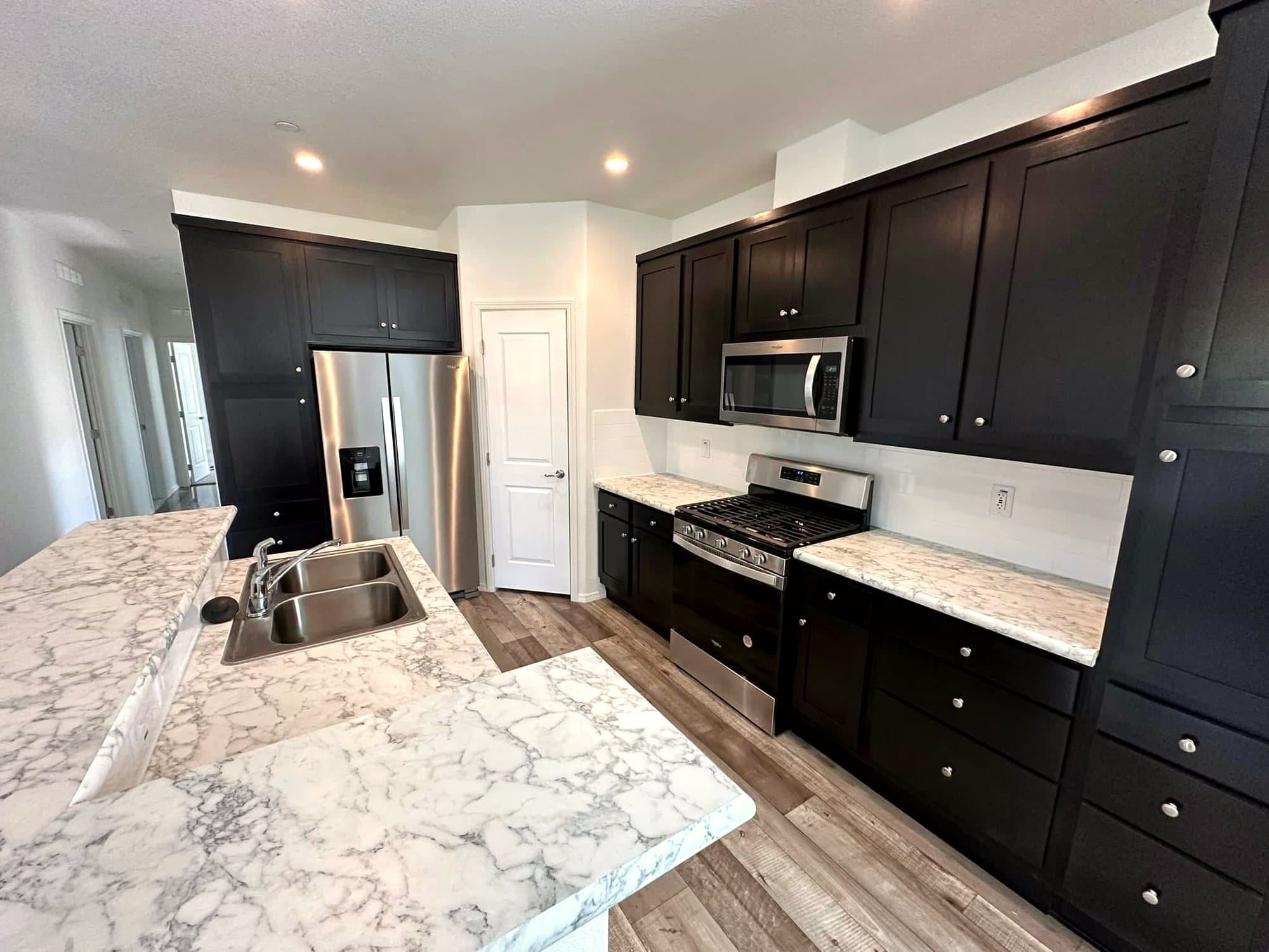 Kitchen with dark cabinets, marble-look counters, and stainless appliances