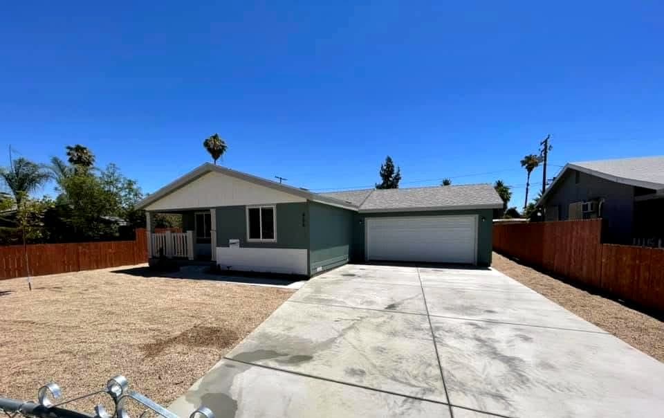 Sage manufactured home with a white garage door and concrete driveway