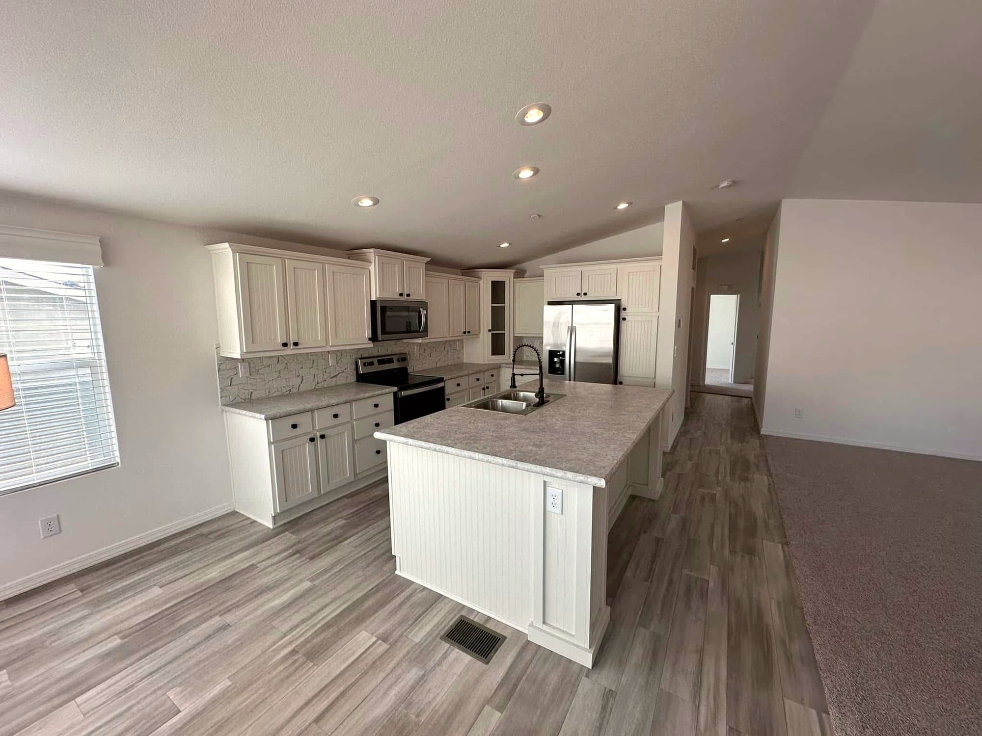 Open kitchen with white cabinets, a large island, and wood-look floors